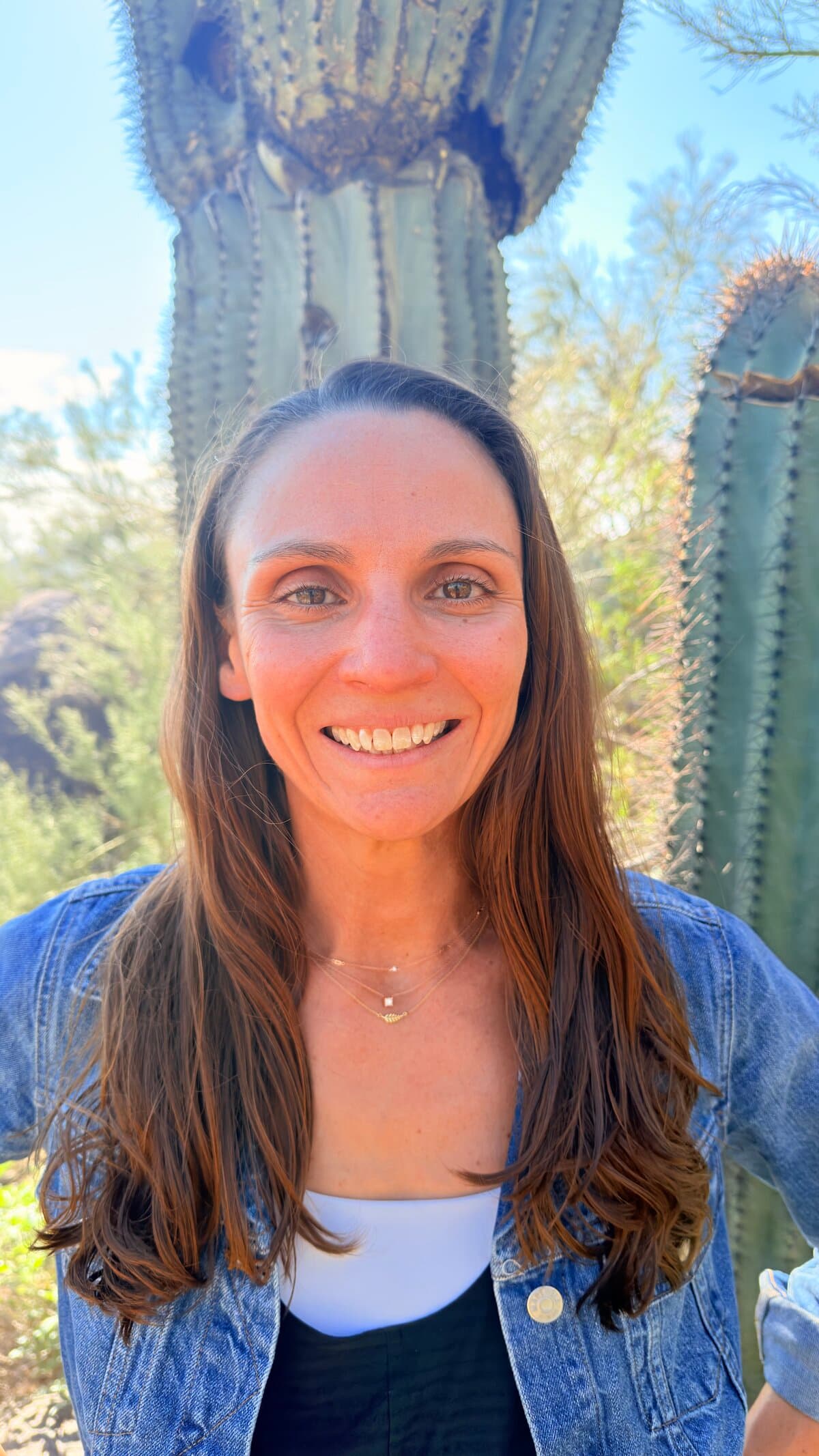 Melissa O'Neal smiling outdoors in front of a tall saguaro cactus, wearing a denim jacket.